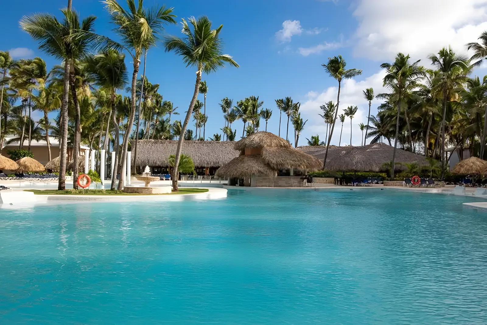 Lagunski bazen sa objektima sa krovom od trske i palmama · Grand Palladium Punta Cana Resort & Spa