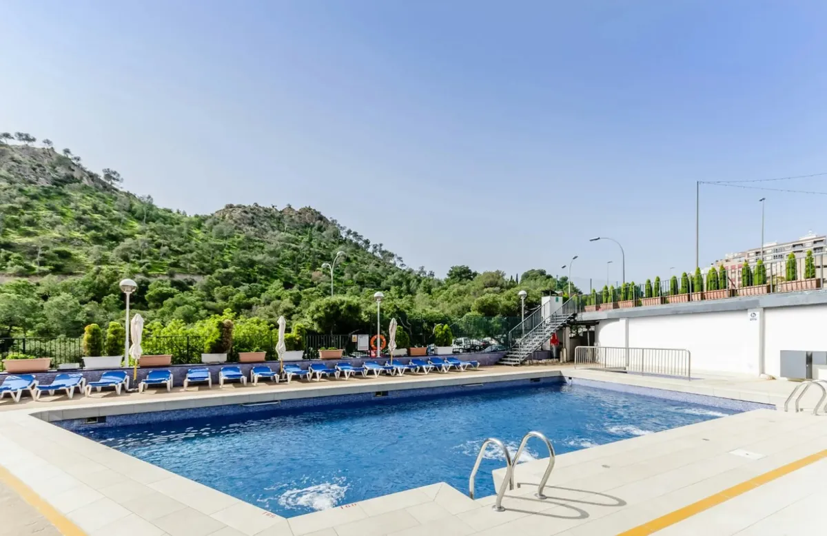 Bazen sa ležaljkama i zelenim brdom u pozadini · Sercotel Maya Alicante, Alikante