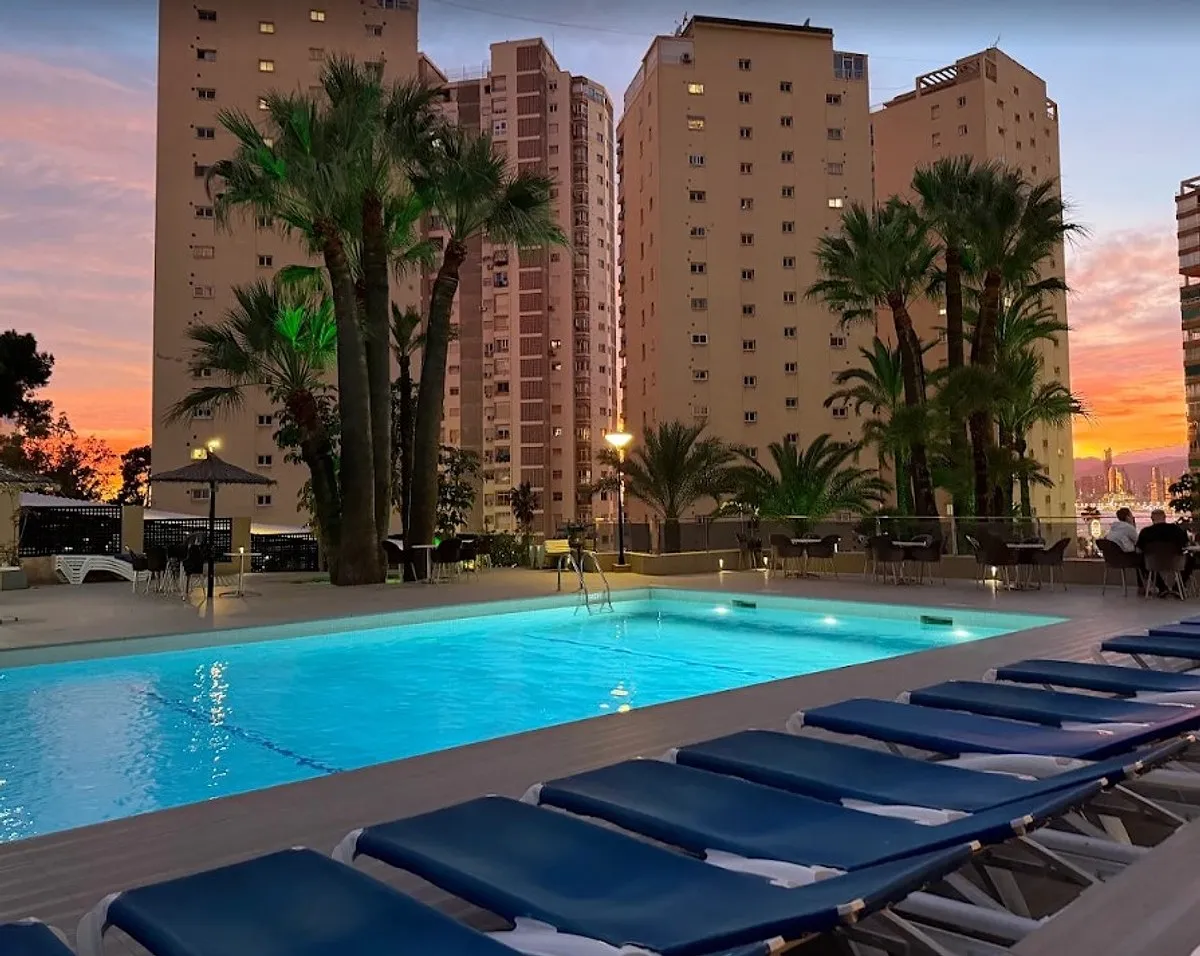 Bazen sa ležaljkama u sumrak okružen palmama · Hotel Las Vegas, Benidorm