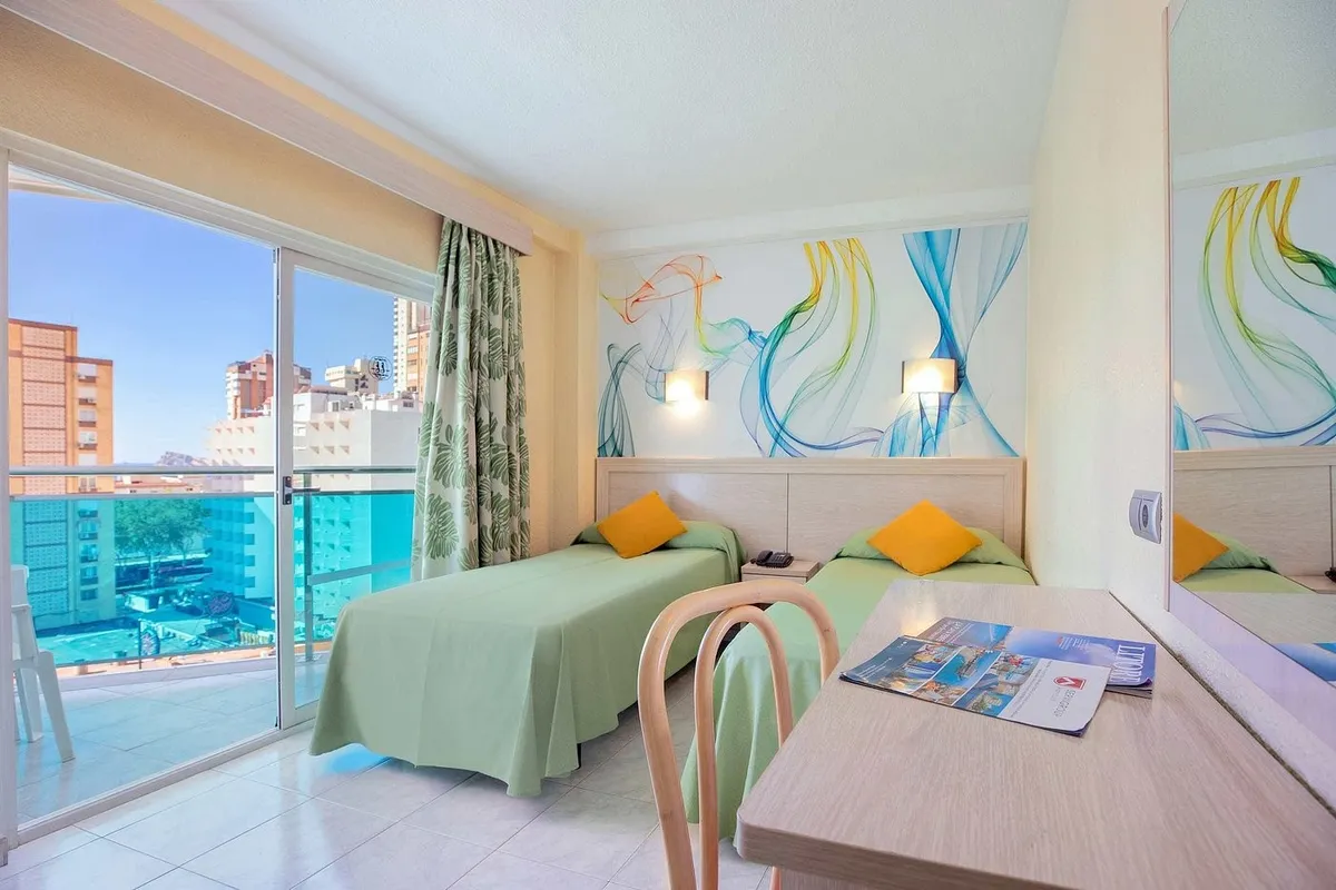 Soba sa dva kreveta sa zelenim prekrivačima i izlazom na balkon · Hotel Servigroup Calypso, Benidorm
