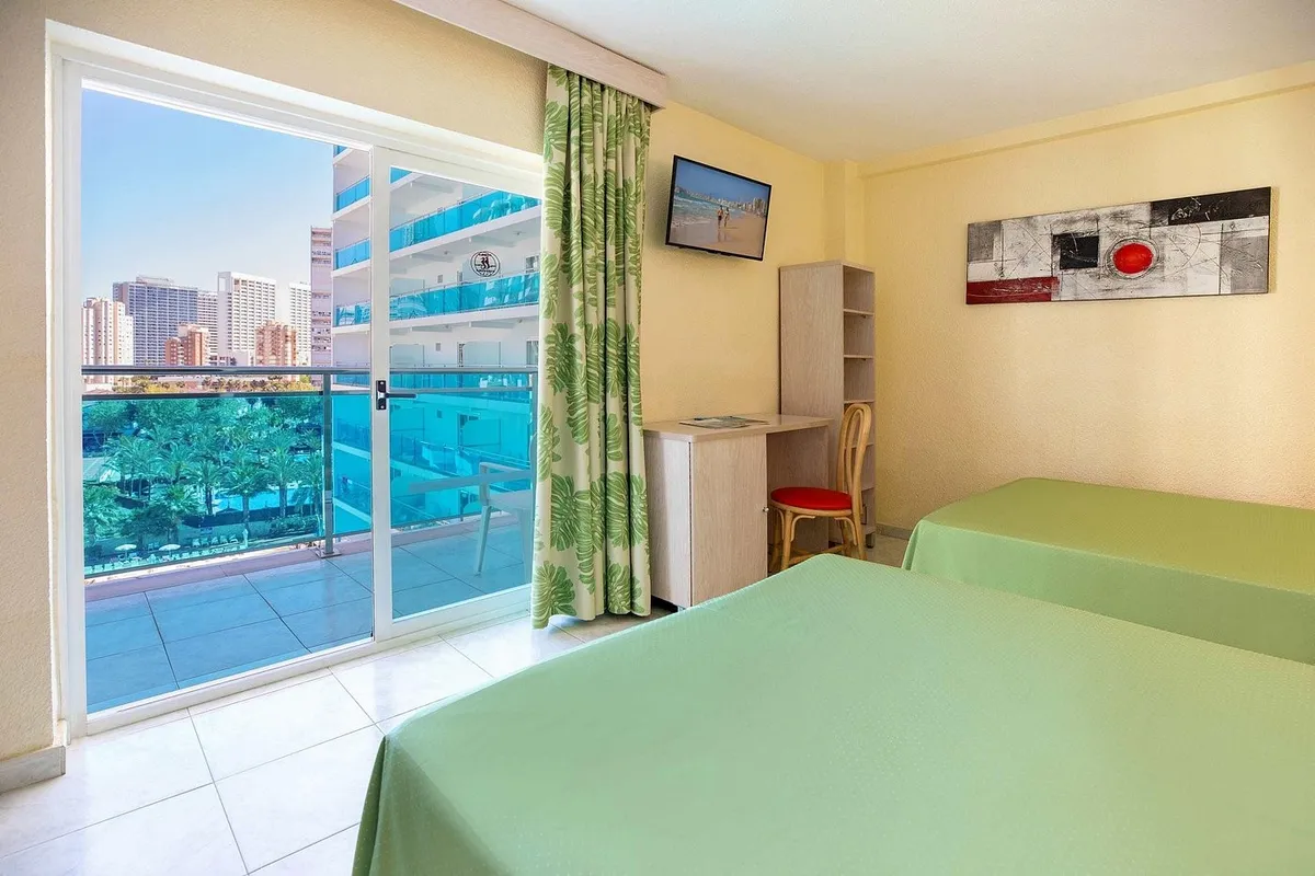 Soba sa balkonskim vratima i zelenim krevetima · Hotel Servigroup Calypso, Benidorm